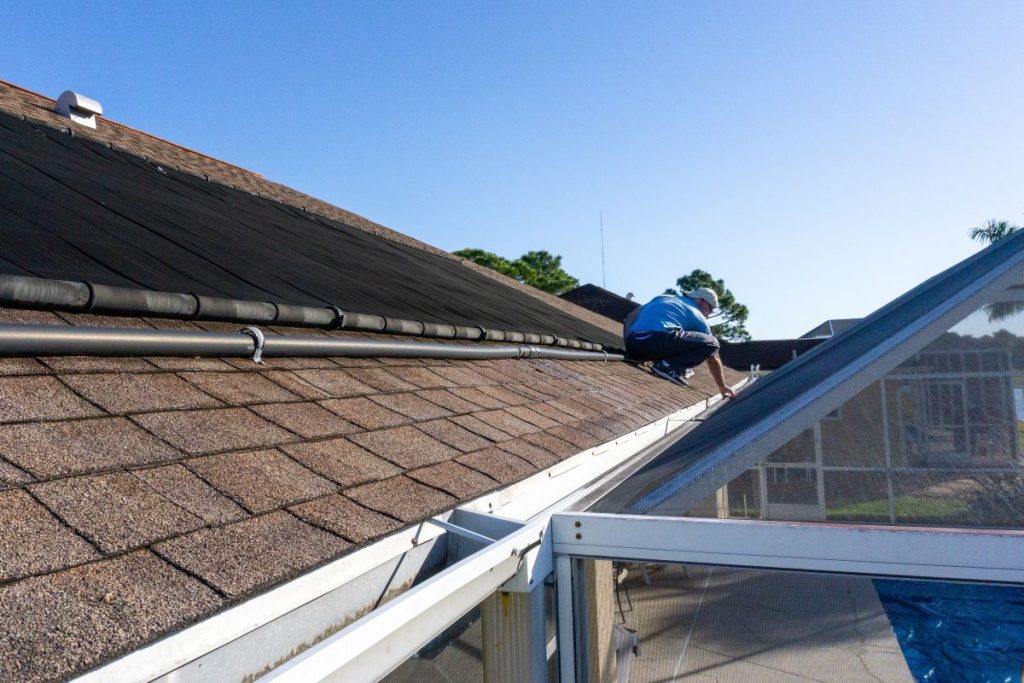 man inspects gutter on roof